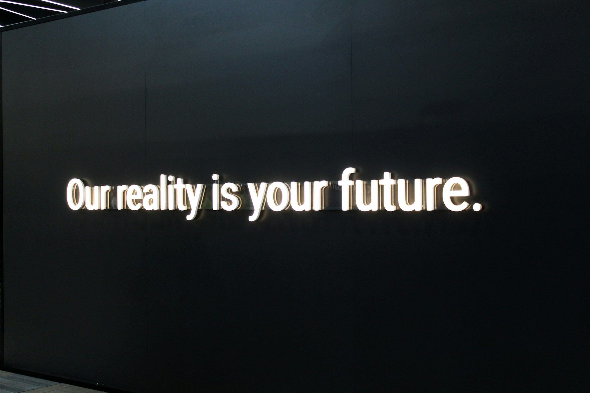 Photo of a wall with the sentence 'Our reality is your future.' in light letters